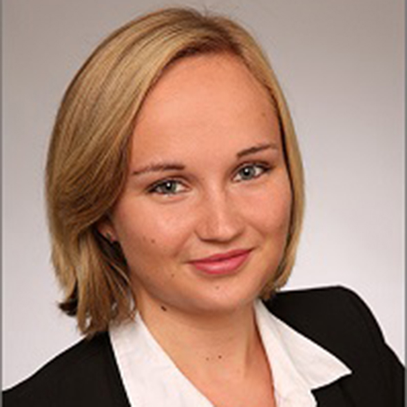 Portraitfoto von einer Frau mit blonden Haaren und blauen Augen vor einem grauen Hintergrund